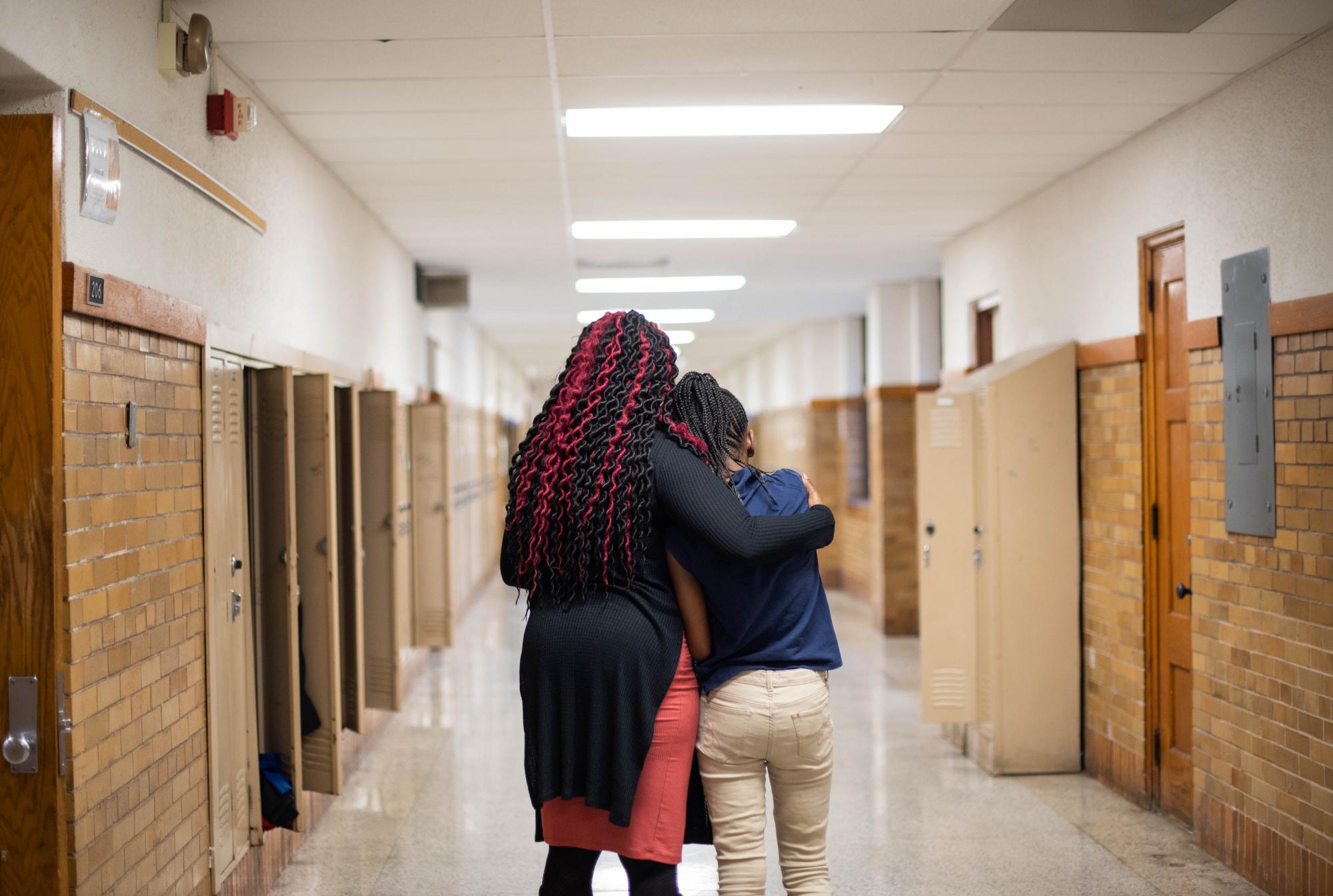 teacher and student together looking down the school hall with teachers arm around student